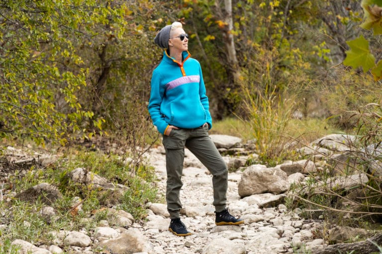 woman in a bright blue fleece on a hiking trail.