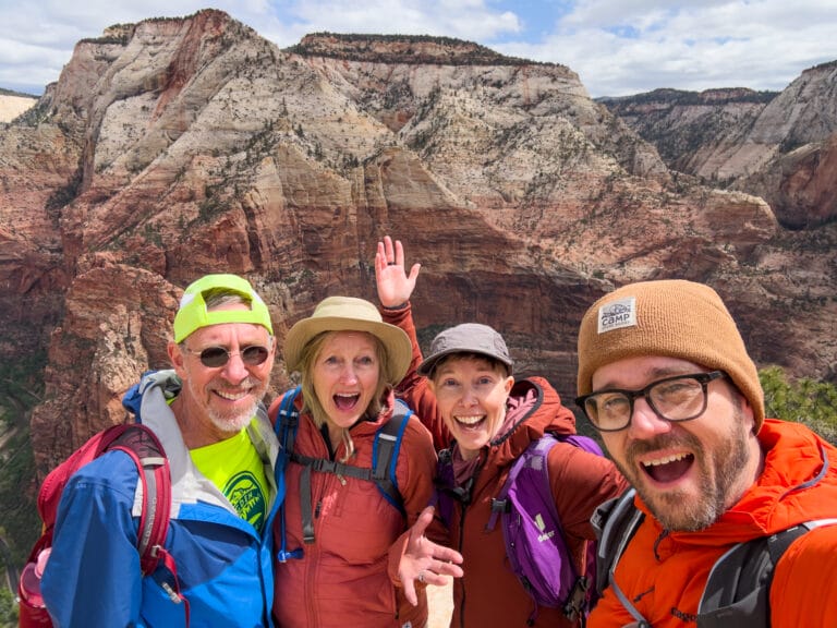 Four people pose smiling at Zion National Park.