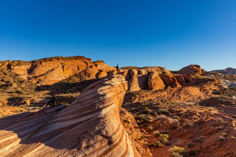 A person stands on top of a massive rock feature at Valley of Fire in Nevada.